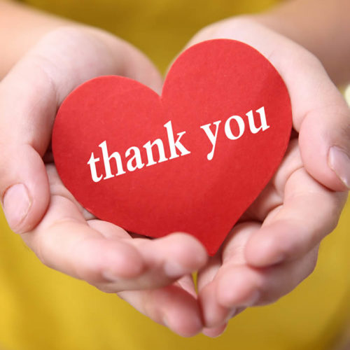 Cupped hands holding a paper heart with thank you on it.