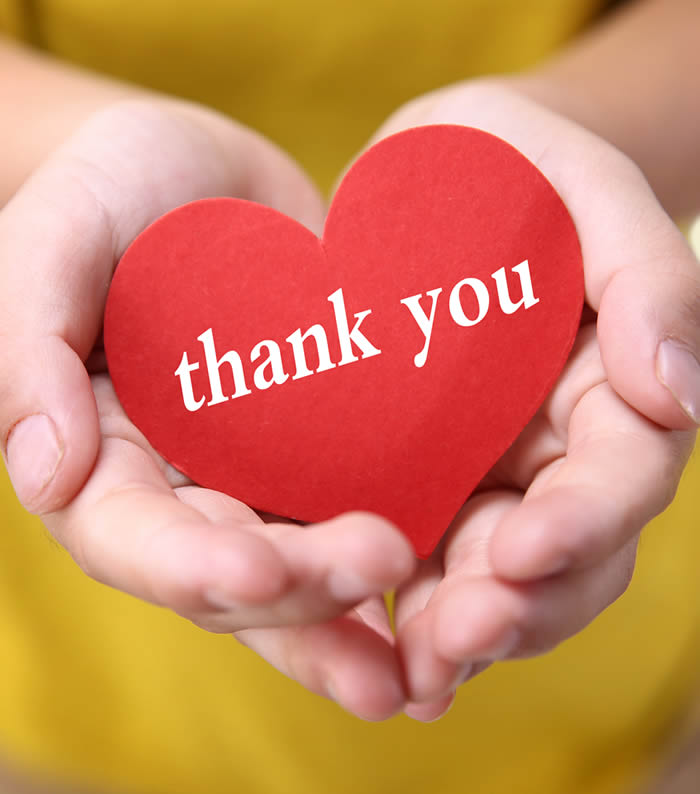 Cupped hands holding a paper heart with thank you on it.